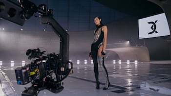 A model wears David Koma, and stands poolside in front of a video camera
