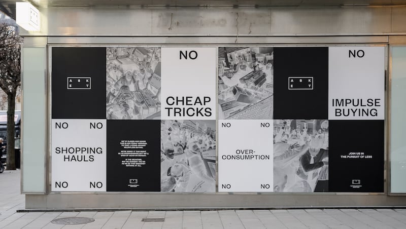 An Asket campaign covers a shop window with messages for shoppers to consumer less.